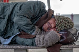 Homeless,Male,Sleeping,On,Stone,Bench,At,Train,Terminal