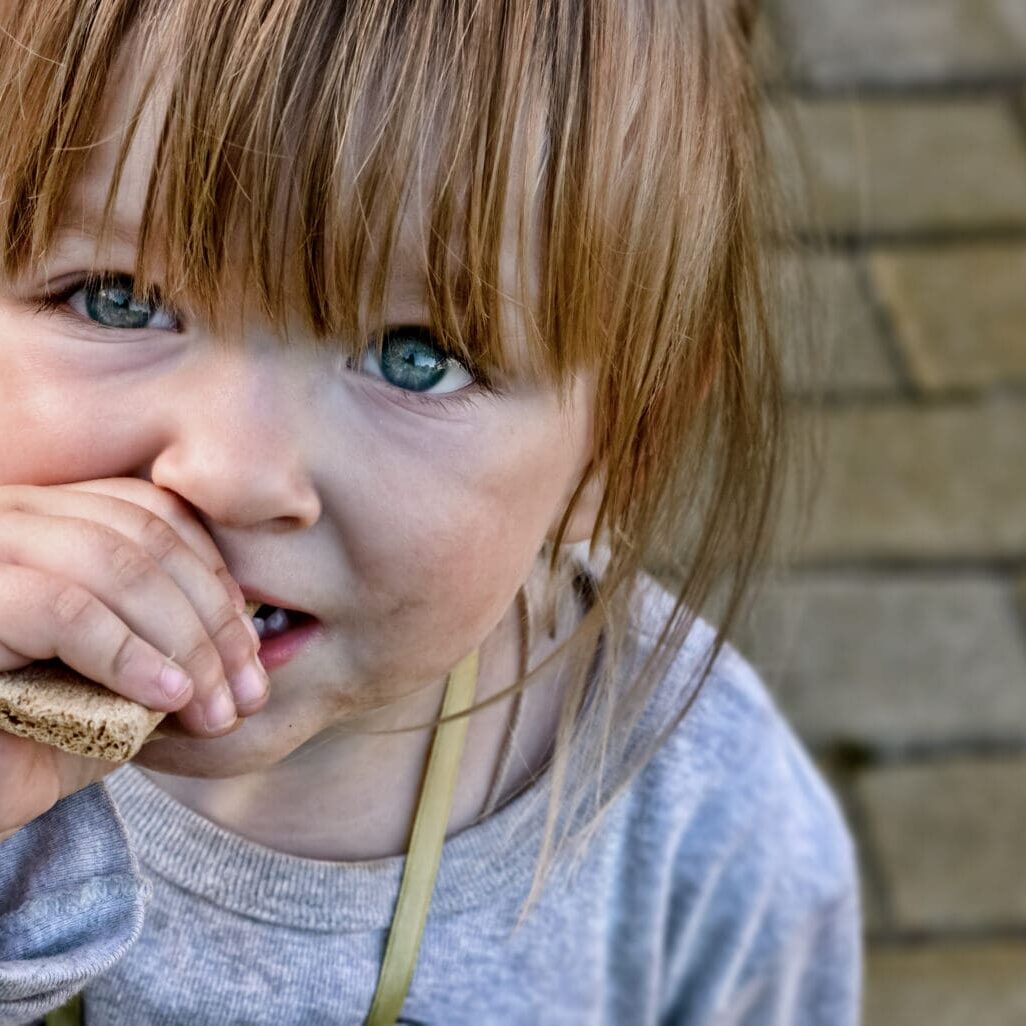 Hungry,Child,With,Big,Clear,Eyes,Eating,Bread,And,Impressively